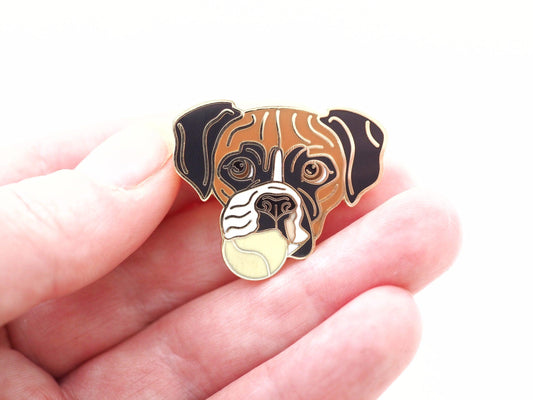 A photo of a Boxer dog Enamel Pin, the dog has a tennis ball in its mouth